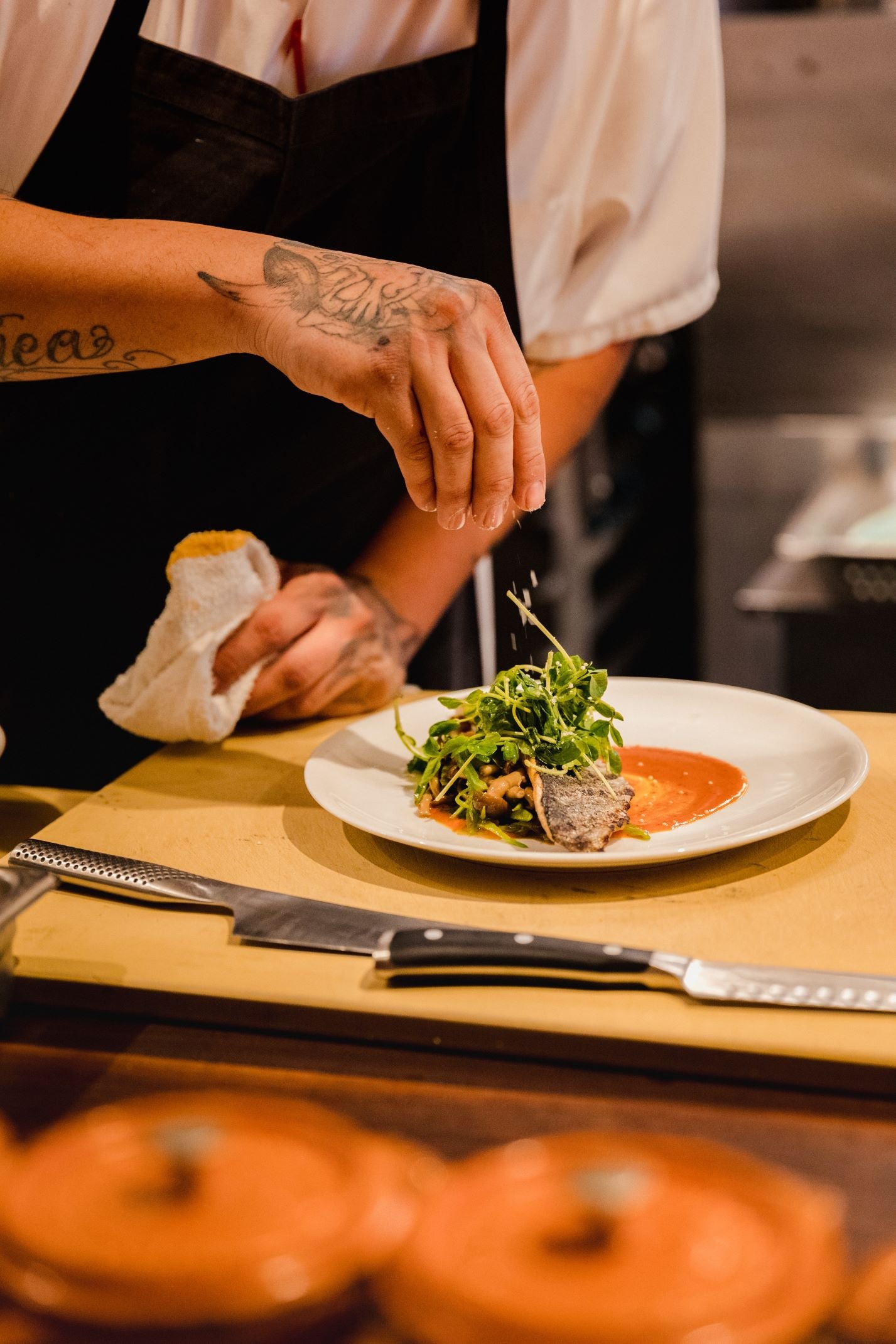 photo of a chef seasoning a plate of food